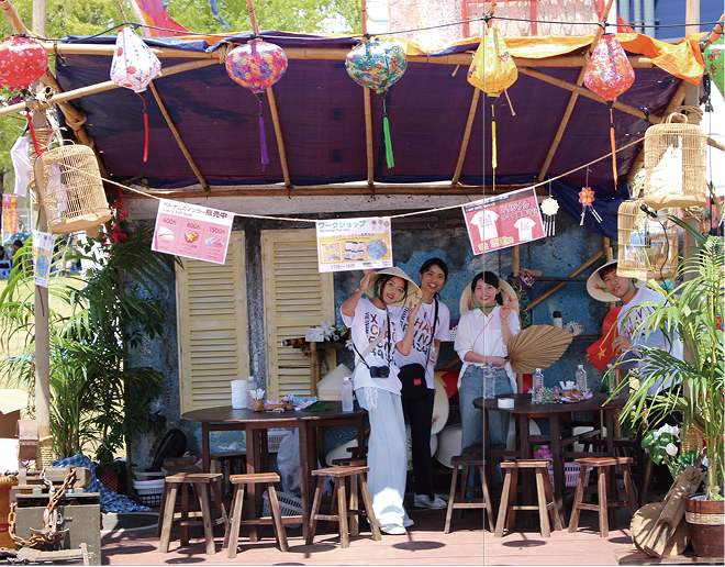 ランタンが飾られた竹製ブースで、ノンラーをかぶった男女4人のスタッフ。ブースには『ノンラー販売中』『ワークショップ ランタン・ノンラー絵付け体験』『オリジナルTシャツ販売中』の案内が掲げられている。