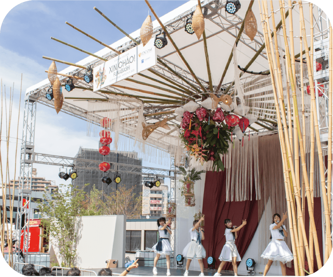青空の下、333ビールの看板が掲げられたベトナム風の建物ブース。入り口には『Xin Mời（シン・モイ）』と書かれた緑のタペストリーとピンクの花が飾られている。
